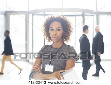 Portrait of young businesswoman with crossed arms standing in office View Large Photo Image Stock Image - Portrait of young businesswoman with crossed arms standing in office. Fotosearch