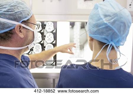 Rear view of surgeons looking at patient's x-ray and MRI scan in operating theater View Large Photo Image Stock Image - Rear view of surgeons looking at patient's x-ray and MRI scan in operating theater. Fotosearch