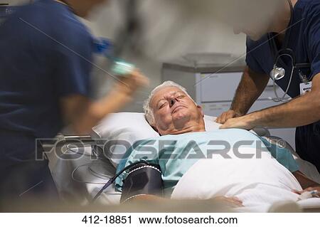 Stock Image - Senior patient receiving medical treatment in intensive care unit. Fotosearch