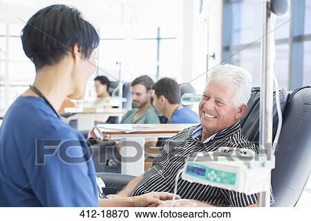 Stock Image - Senior patient undergoing medical treatment talking to doctor in outpatient clinic. Fotosearch