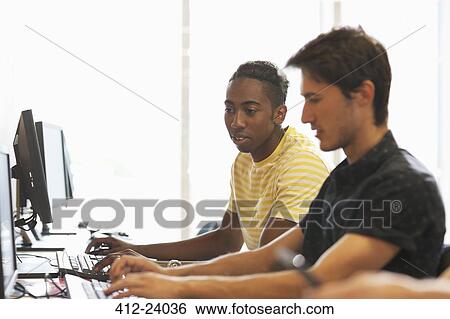 Stock Photograph - Side view of university students studying on computers in classroom. Fotosearch