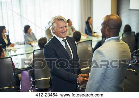 Picture - Smiling businessmen shaking hands during meeting in conference room. Fotosearch