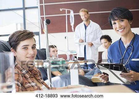 Smiling doctors checking with patients undergoing medical treatment in outpatient clinic View Large Photo Image Stock Image - Smiling doctors checking with patients undergoing medical treatment in outpatient clinic. Fotosearch