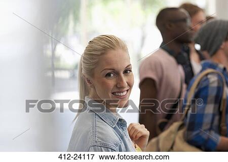 Smiling female student looking at camera with other students in background View Large Photo Image Stock Photo - Smiling female student looking at camera with other students in background. Fotosearch