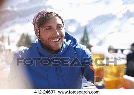 Smiling man in warm clothing drinking beer outdoors View Large Photo Image Stock Photo - Smiling man in warm clothing drinking beer outdoors. Fotosearch