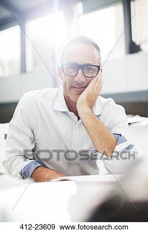 Stock Photo - Smiling older man sitting at desk. Fotosearch