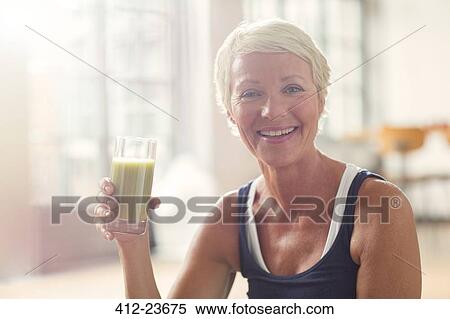 Stock Photography - Smiling older woman drinking juice. Fotosearch