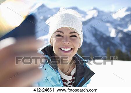 Stock Image - Smiling woman taking selfie in snow. Fotosearch