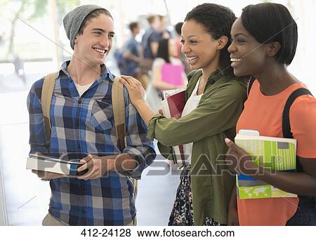 Students holding books and laughing with other students in background View Large Photo Image Stock Photo - Students holding books and laughing with other students in background. Fotosearch