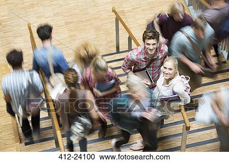 Stock Image - Students looking at camera and standing on stairs during break time. Fotosearch
