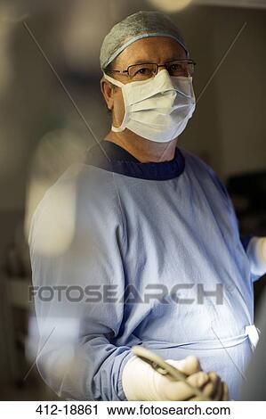 Surgeon wearing surgical mask, cap, gloves and gown in operating theater View Large Photo Image Stock Image - Surgeon wearing surgical mask, cap, gloves and gown in operating theater. Fotosearch