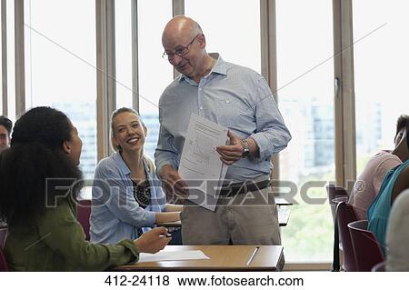 Stock Photo - Teacher talking with students during lecture in sunlit classroom. Fotosearch
