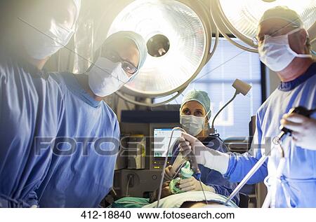 Stock Image - Team of doctors performing laparoscopic surgery in operating theater. Fotosearch