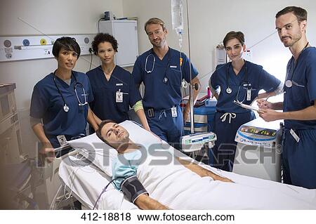 Team of doctors standing around smiling patient lying in bed in intensive care unit View Large Photo Image Stock Photo - Team of doctors standing around smiling patient lying in bed in intensive care unit. Fotosearch