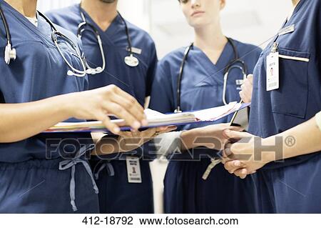 Stock Image - Team of doctors with stethoscopes looking at documents in hospital. Fotosearch