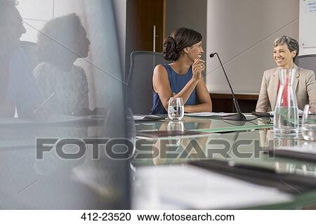 Three businesswomen sitting and talking at conference table View Large Photo Image Stock Image - Three businesswomen sitting and talking at conference table. Fotosearch