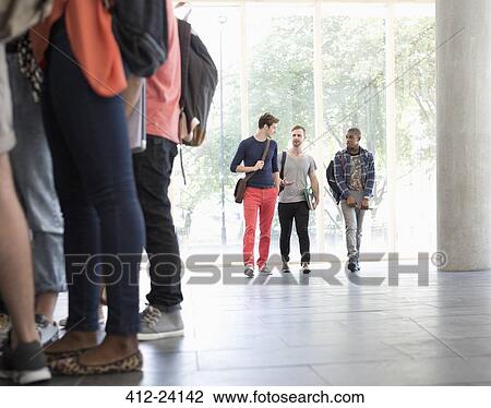 Three male students walking along corridor talking with large window in background View Large Photo Image Stock Image - Three male students walking along corridor talking with large window in background. Fotosearch