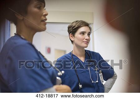 Stock Photo - Two female doctors wearing navy blue scrubs, talking in hospital. Fotosearch