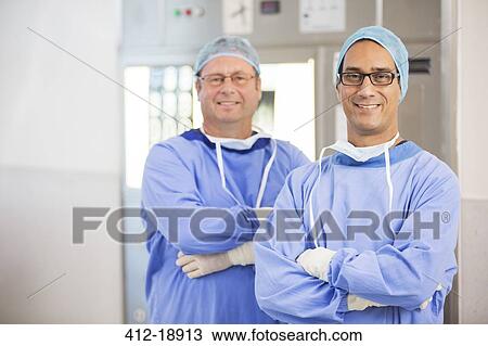 Two smiling doctors with arms crossed, wearing surgical clothing and eyeglasses in hospital View Large Photo Image Stock Image - Two smiling doctors with arms crossed, wearing surgical clothing and eyeglasses in hospital. Fotosearch