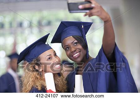Two smiling female students taking selfie after graduation View Large Photo Image Stock Photo - Two smiling female students taking selfie after graduation. Fotosearch