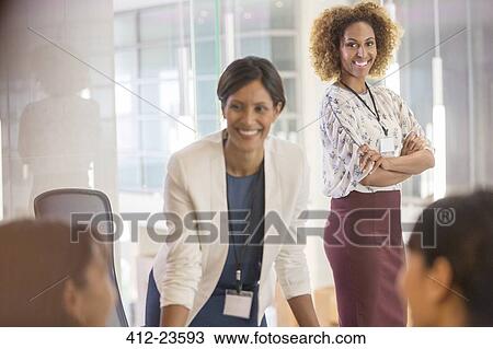 Stock Image - Two women standing in conference room. Fotosearch