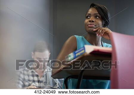 University student sitting at desk with hand on chin View Large Photo Image Stock Photo - University student sitting at desk with hand on chin. Fotosearch