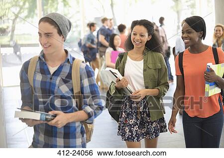 Stock Photograph - University students carrying books and walking to classroom. Fotosearch