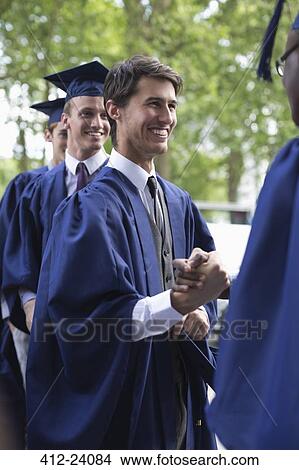 Picture - University students congratulating one another after graduation ceremony. Fotosearch