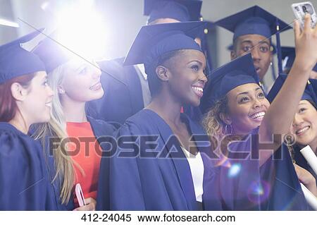 Stock Photography - University students taking selfie in corridor after graduation ceremony. Fotosearch