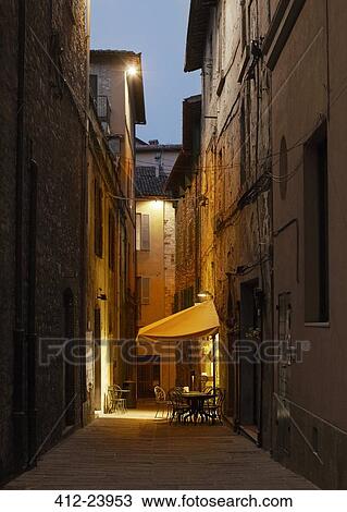View of cafe table in town alley illuminated at dusk View Large Photo Image Stock Image - View of cafe table in town alley illuminated at dusk. Fotosearch