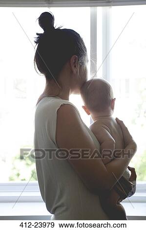 View of mother holding baby and looking through window View Large Photo Image Stock Photo - View of mother holding baby and looking through window . Fotosearch
