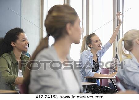 View of smiling female students sitting at desks in classroom View Large Photo Image Stock Image - View of smiling female students sitting at desks in classroom . Fotosearch