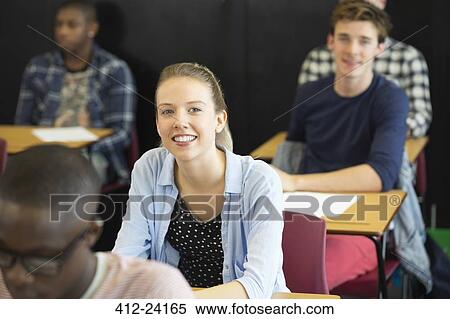 View of smiling students sitting at desks in classroom View Large Photo Image Stock Photography - View of smiling students sitting at desks in classroom. Fotosearch