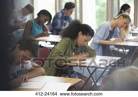 View of students sitting at desks during test in classroom View Large Photo Image Picture - View of students sitting at desks during test in classroom . Fotosearch