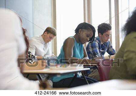 Stock Photograph - View of students sitting at desks during test in classroom . Fotosearch