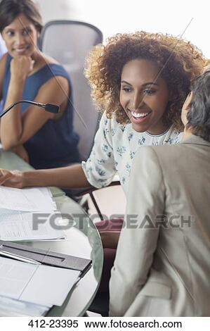 Stock Photography - Young businesswoman listening carefully to her elder colleague during business meeting. Fotosearch