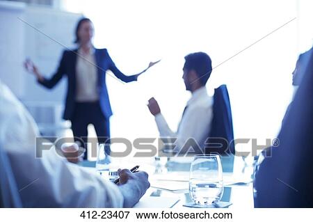 Stock Photo - Young businesswoman standing in conference room giving presentation. Fotosearch