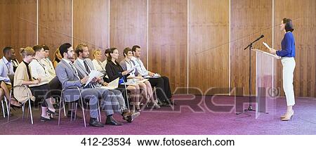 Young woman standing at transparent lectern, talking before audience in conference room View Large Photo Image Picture - Young woman standing at transparent lectern, talking before audience in conference room. Fotosearch