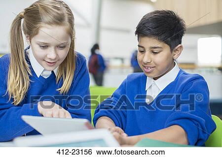Boy and girl wearing school uniforms using digital tablet together View Large Photo Image Stock Photograph - Boy and girl wearing school uniforms using digital tablet together. Fotosearch