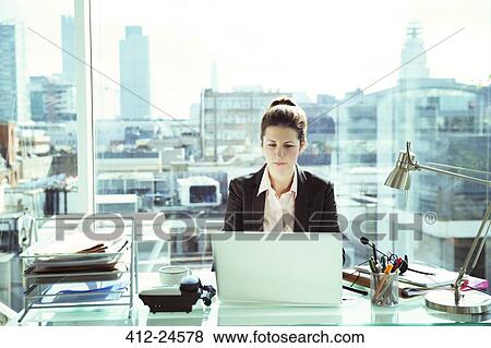 Stock Photo - Businesswoman working on laptop in office. Fotosearch