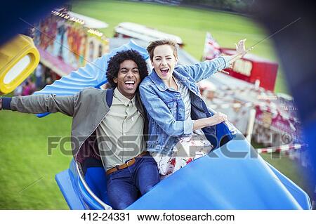 Cheerful couple having fun on carousel in amusement park View Large Photo Image Stock Image - Cheerful couple having fun on carousel in amusement park. Fotosearch