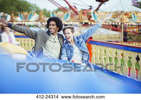 Picture - Cheerful couple on carousel in amusement park. Fotosearch