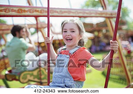 Cheerful girl laughing on carousel in amusement park View Large Photo Image Stock Image - Cheerful girl laughing on carousel in amusement park. Fotosearch