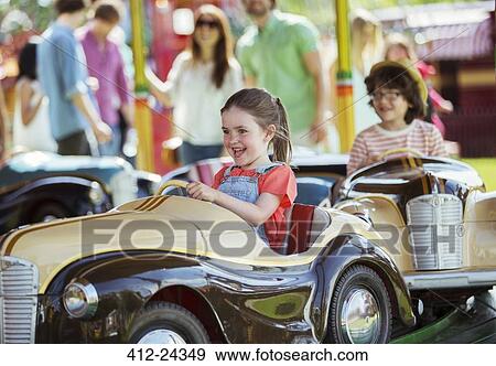 Stock Photo - Cheerful girl on carousel in amusement park. Fotosearch
