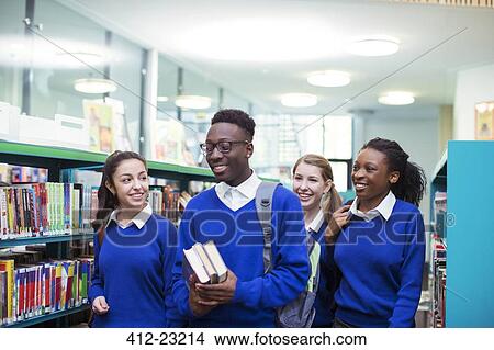 Picture - Cheerful students wearing blue school uniforms walking through library. Fotosearch