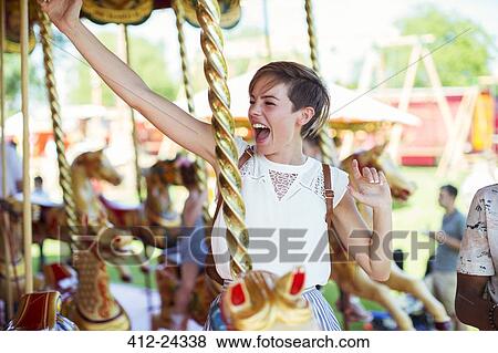 Cheerful woman sitting on horse on carousel in amusement park View Large Photo Image Stock Photo - Cheerful woman sitting on horse on carousel in amusement park. Fotosearch