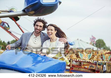 Couple enjoying ride on carousel in amusement park View Large Photo Image Stock Photograph - Couple enjoying ride on carousel in amusement park. Fotosearch