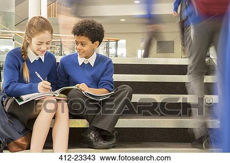 Elementary school children wearing school uniforms sitting on steps and writing in textbooks View Large Photo Image Stock Image - Elementary school children wearing school uniforms sitting on steps and writing in textbooks. Fotosearch
