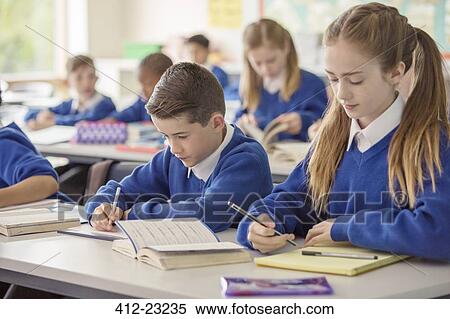 Elementary school children working at desk in classroom during lesson View Large Photo Image Stock Photography - Elementary school children working at desk in classroom during lesson. Fotosearch