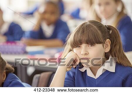 Elementary schoolgirl looking bored during lesson View Large Photo Image Stock Photo - Elementary schoolgirl looking bored during lesson. Fotosearch